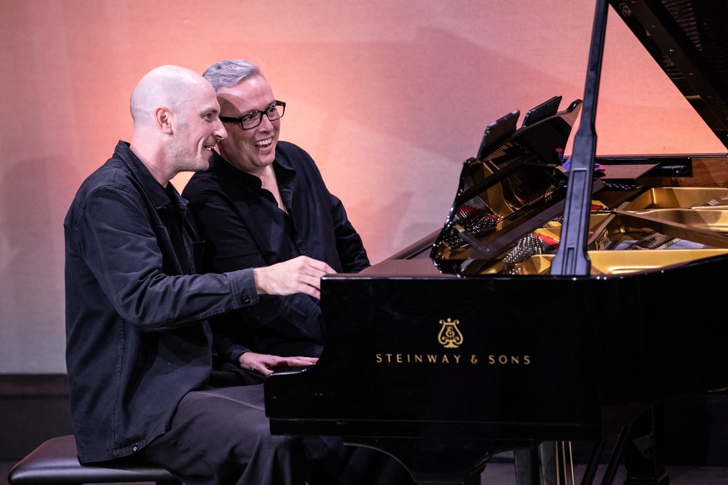 Luis Magalhães and Caspar Vos laughing while playing four hands at one Steinway