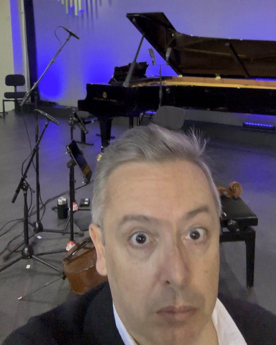 Luis Magalhães taking a wide-eyed selfie on the stage of De Stag with the piano behind him
